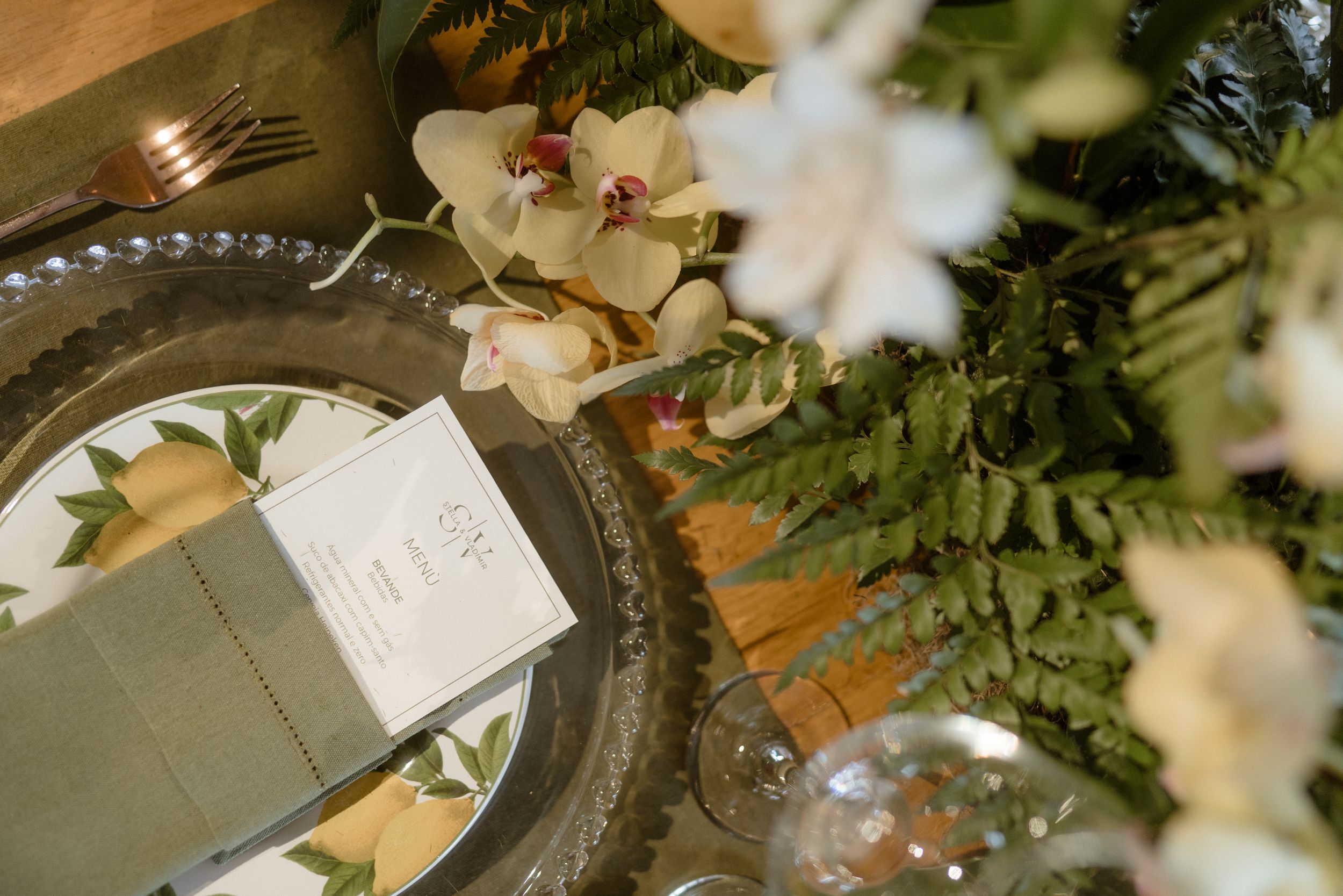 Wedding place setting with menu card and floral details on silver charger plate.