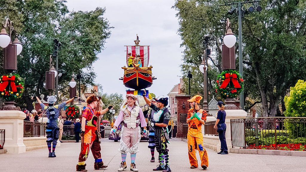 Colorfully dressed characters pose in front of a castle with holiday decorations at Walt Disney World in Orlando.