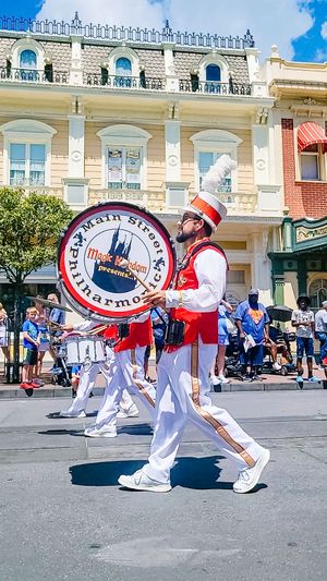 A marching band member performs with a bass drum at Disney World's Main Street USA during a parade celebration.