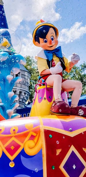 Colorful parade float features animated characters sitting on vibrant red and purple platforms against a blue sky.