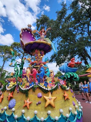Colorful Disney parade float featuring sea creatures, stars and characters on display at Magic Kingdom theme park.
