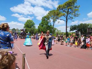 Families gather outdoors at Animal Kingdom theme park enjoying a sunny summer day with decorative plants nearby.