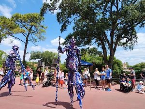 A sequence of outdoor event scenes showing a crowd gathered on a sunny day with trees and blue skies in the background.