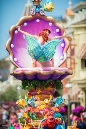 Colorful parade float featuring enchanted seashell designs and whimsical fish characters at Disney theme park celebration.
