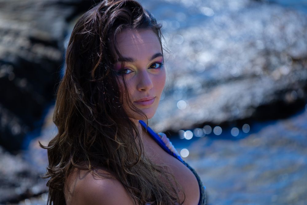 Close-up portrait of person with wet hair against blurred ocean background.