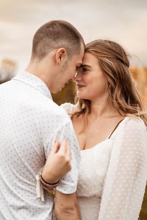 Close-up romantic portraits of couple in matching white outfits against soft natural lighting.