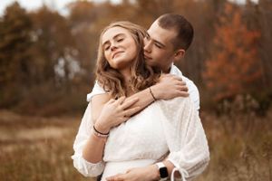 Intimate autumn photoshoot in a golden field with couple in white and casual attire.