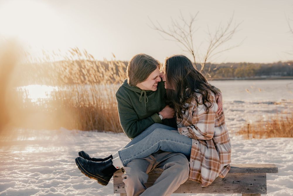 A couple sharing intimate moments together on a bench at sunset.