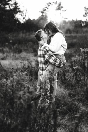 Black and white photo of couple sharing romantic moment in field.
