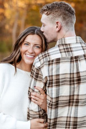 Couple laughing and embracing in casual autumn outfits during outdoor photoshoot.