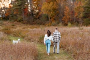 Couple walking through autumn landscape during golden hour.