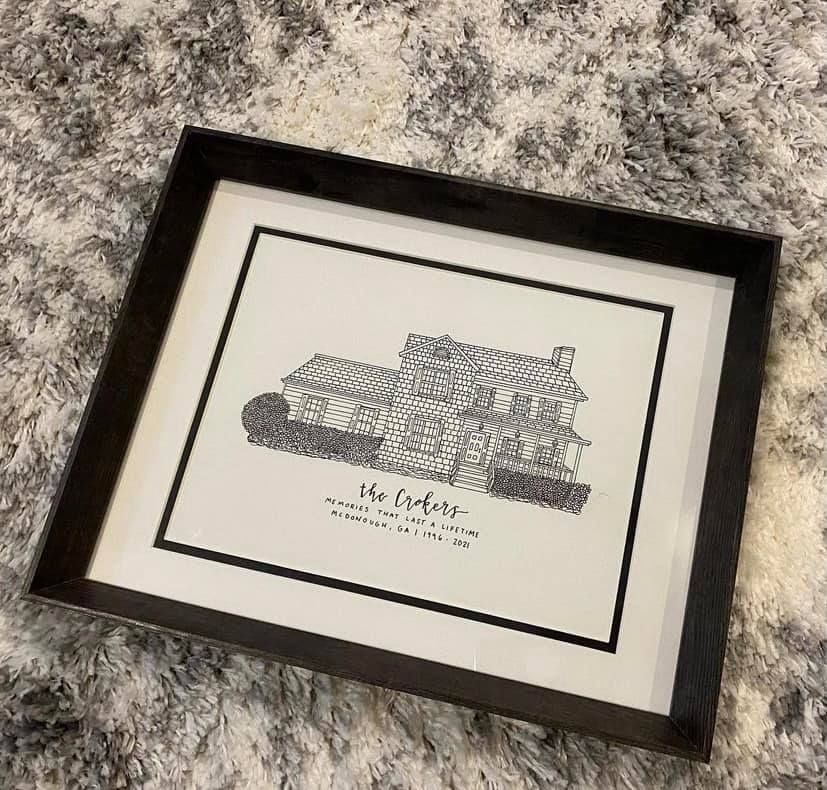 Professionally framed black and white architectural sketch of a brick colonial home.