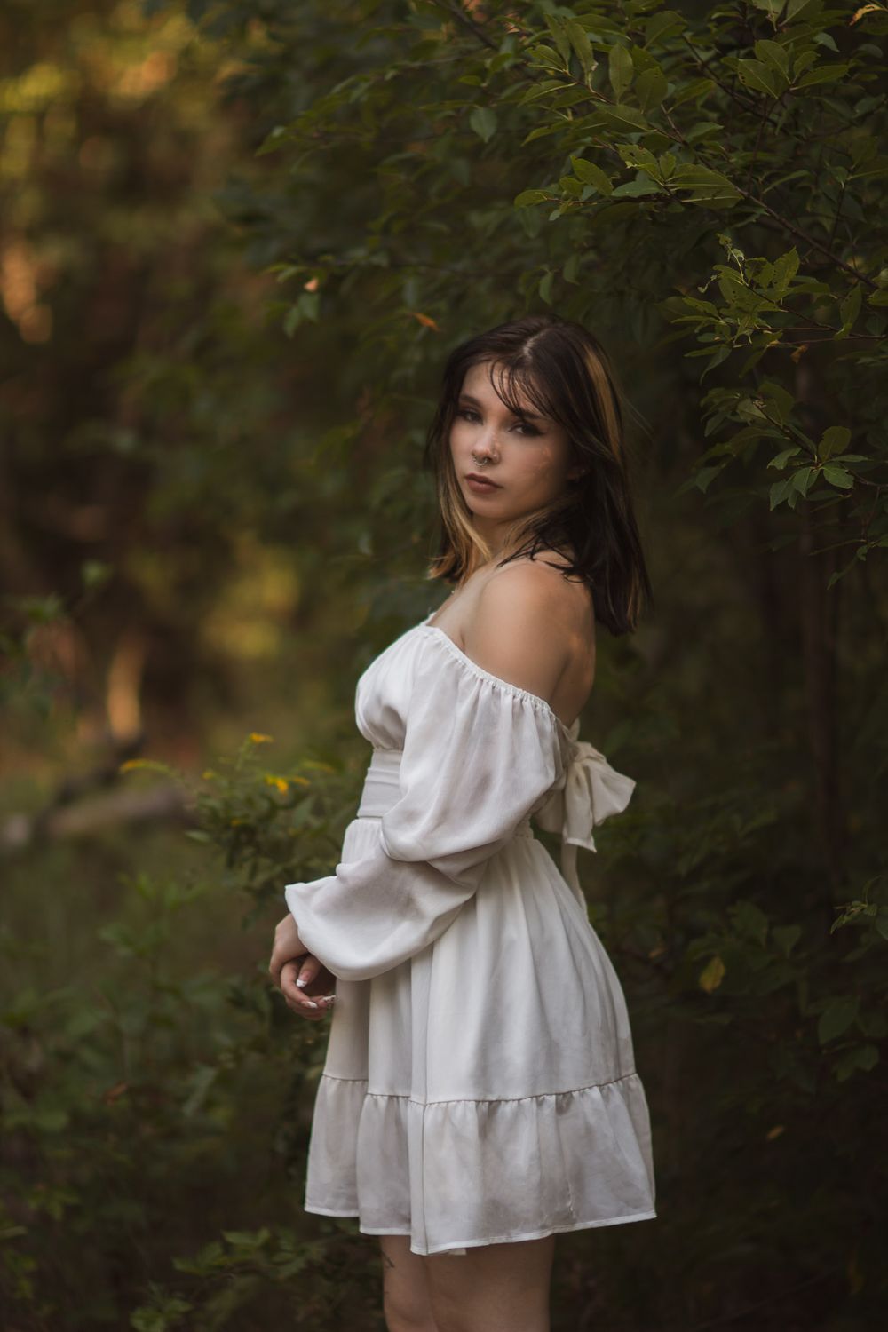 Girl looking stoically at camera in a flowing white dress during an outdoor photoshoot in Joplin, Missouri.