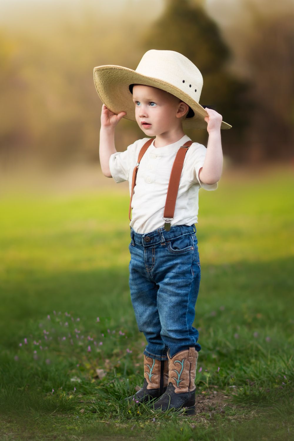 Boy holding his hat in a Seneca field during a family photoshoot by Joplin photographer