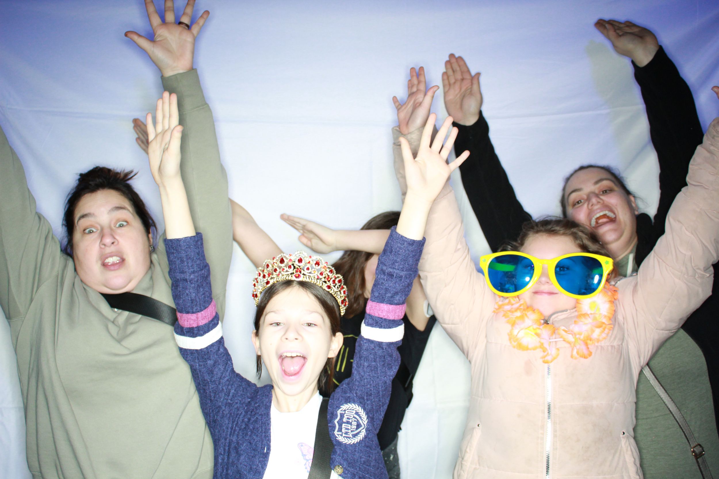 Group of people jumping and raising their arms in excitement with a person wearing bright yellow sunglasses.