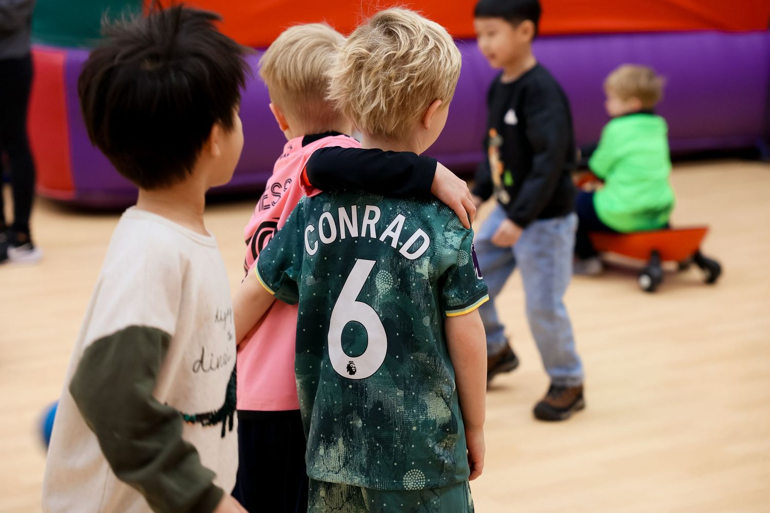 Children playing at an indoor activity center, with one child wearing a green jersey. Event and Birthday Photography by Smilein.