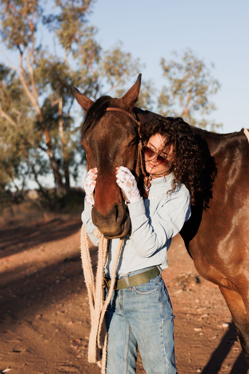 Horse and rider sharing an affectionate moment on a dirt trail.