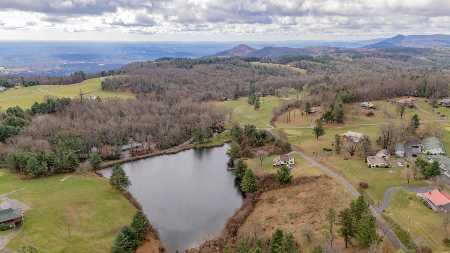 Aerial view of a scenic lake surrounded by rolling hills and rural countryside.