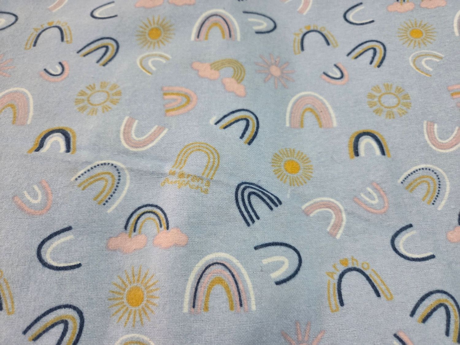 Whimsical pattern of pastel rainbows, suns, and curved lines on a light blue background in a playful doodle style.