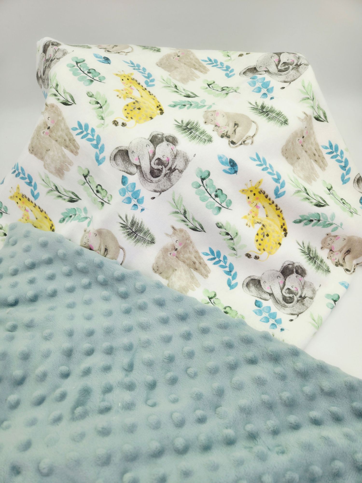 Baby blanket with safari animal print pattern paired with light blue minky fabric.