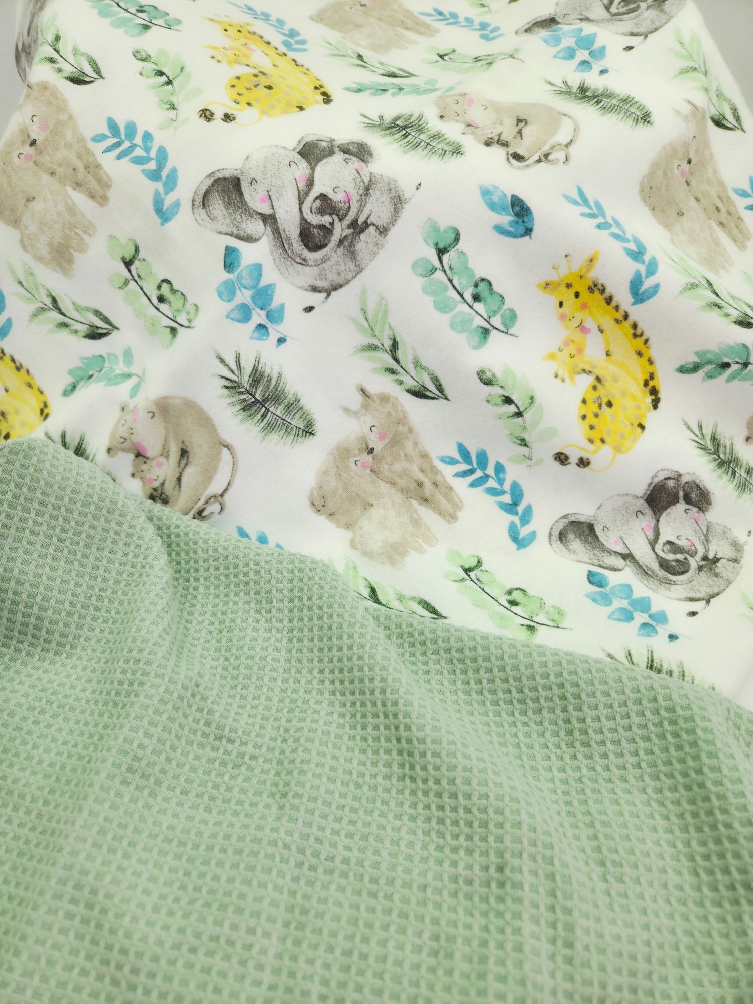 Baby blanket featuring cute safari animals and floral patterns on white fabric with mint green waffle texture backing.