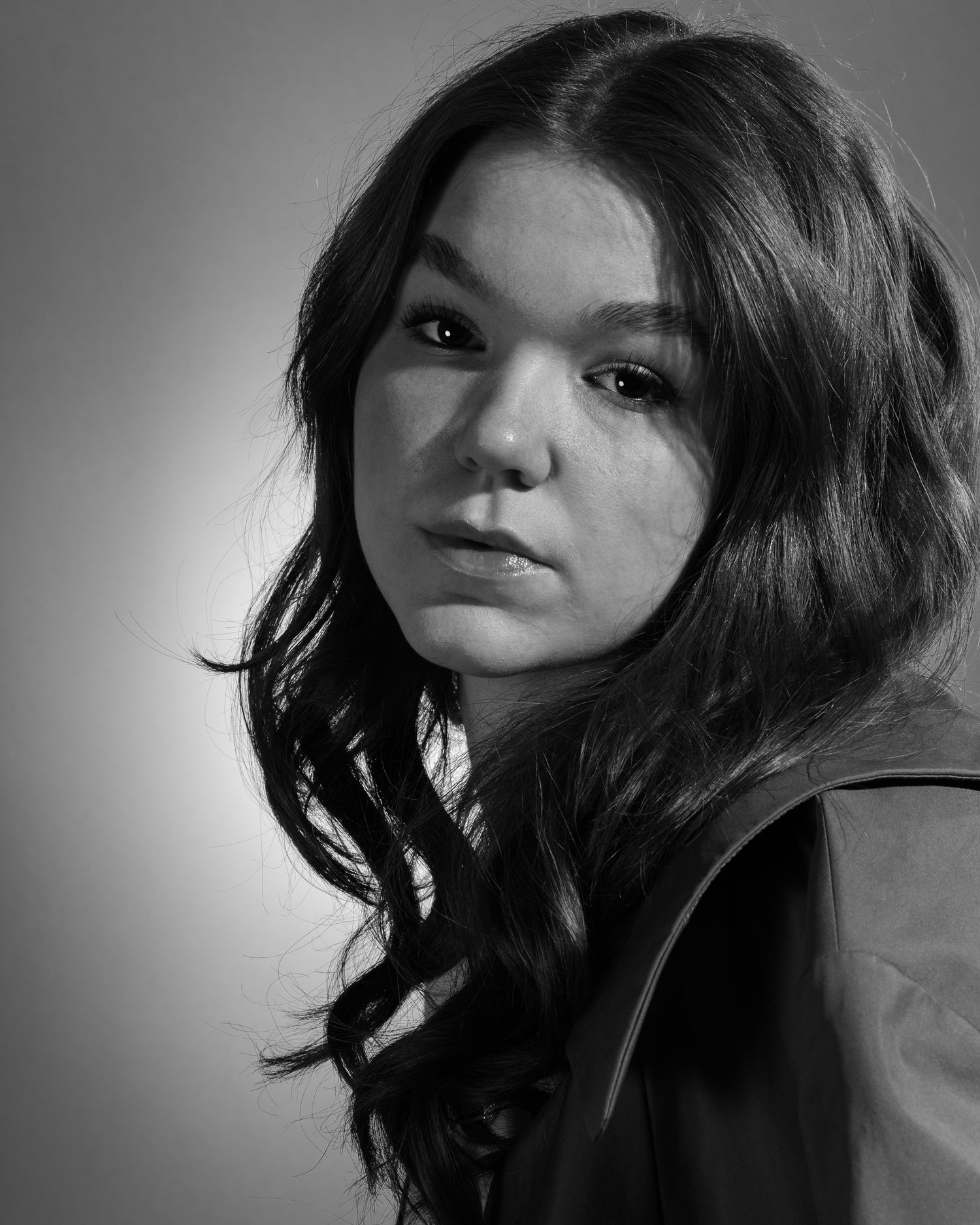 Dramatic black and white portrait with moody lighting and textured hair.