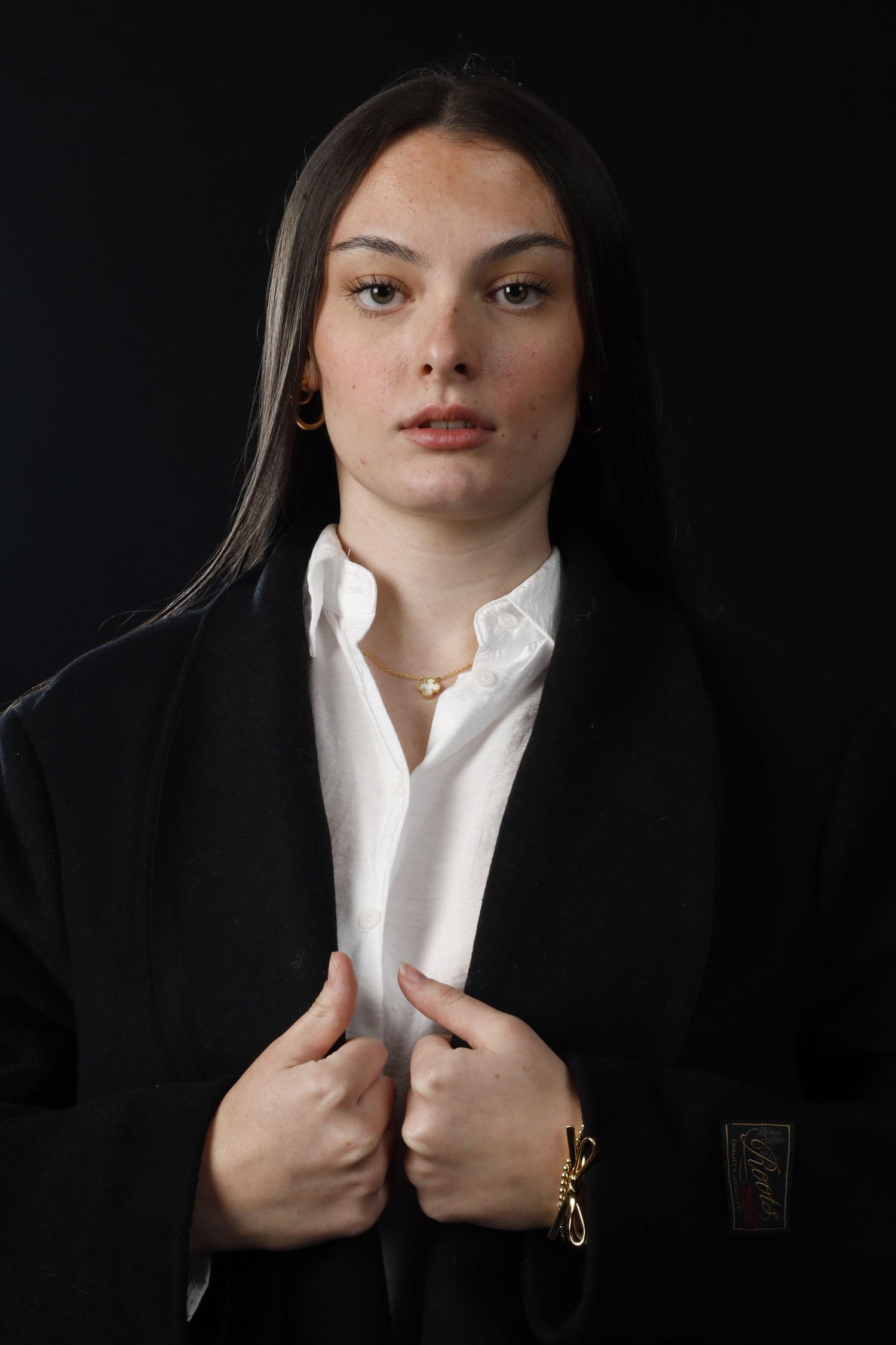 Professional portrait in classic black blazer and white shirt against dark background.