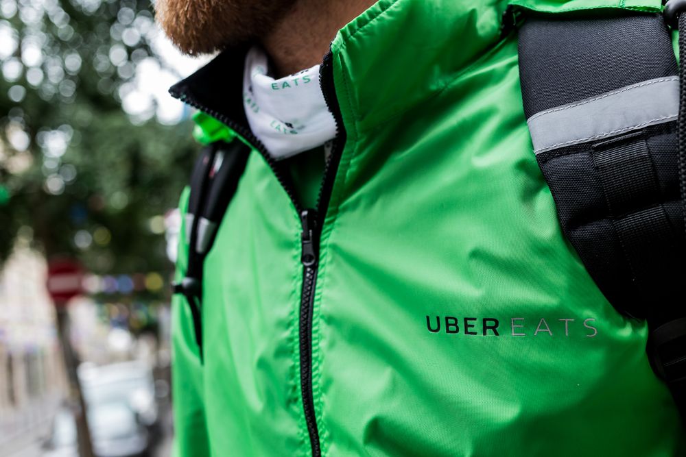 Close-up view of bright green Uber Eats delivery jacket with logo and zipper detail.