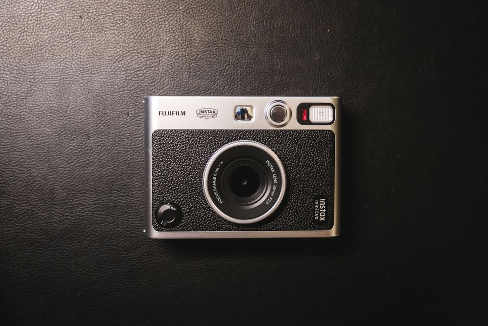 A Fuji Instax Mini Evo on a black leather background.