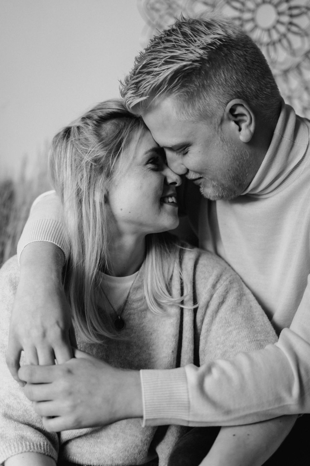 A tender black and white portrait of an intimate couple sharing a close romantic moment in matching sweaters.