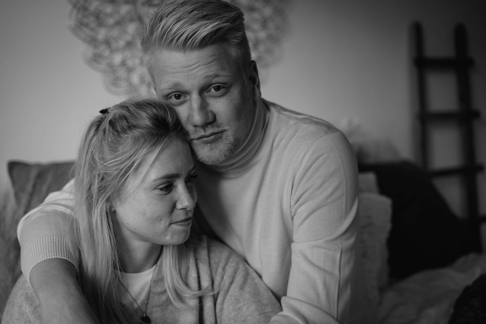 A black and white intimate portrait of an affectionate couple embracing on a couch.