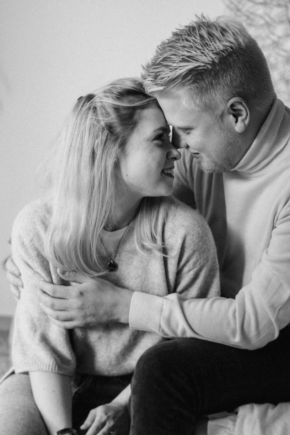 A romantic black and white portrait of a couple in cozy sweaters sharing an intimate moment together.
