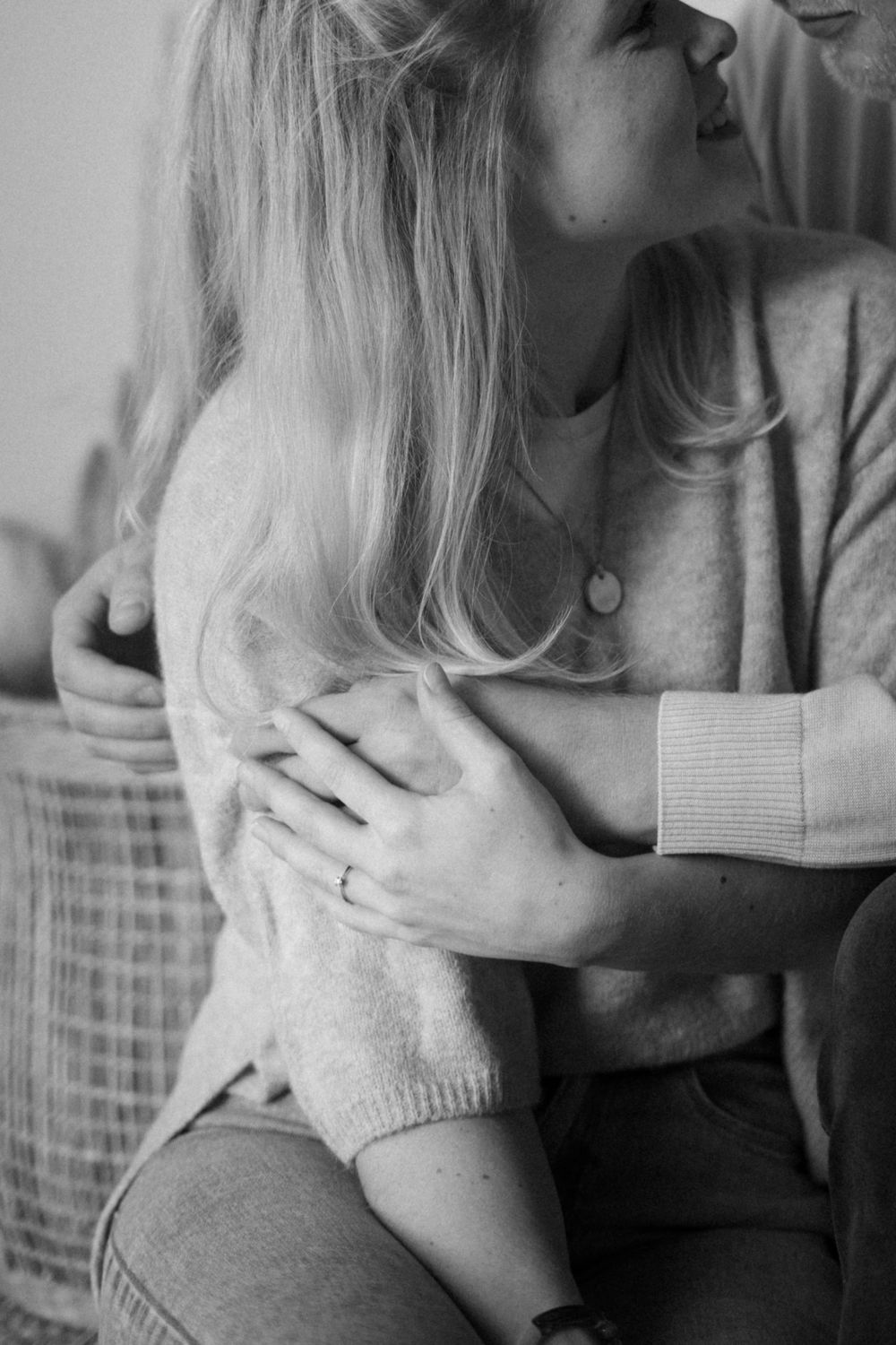 A romantic black and white moment showing hands embracing in cozy sweaters.