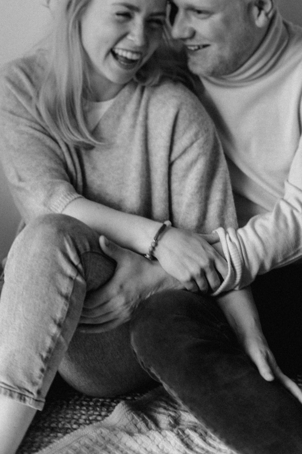 Intimate black and white photo showing a joyful couple sharing a tender moment in matching sweaters.