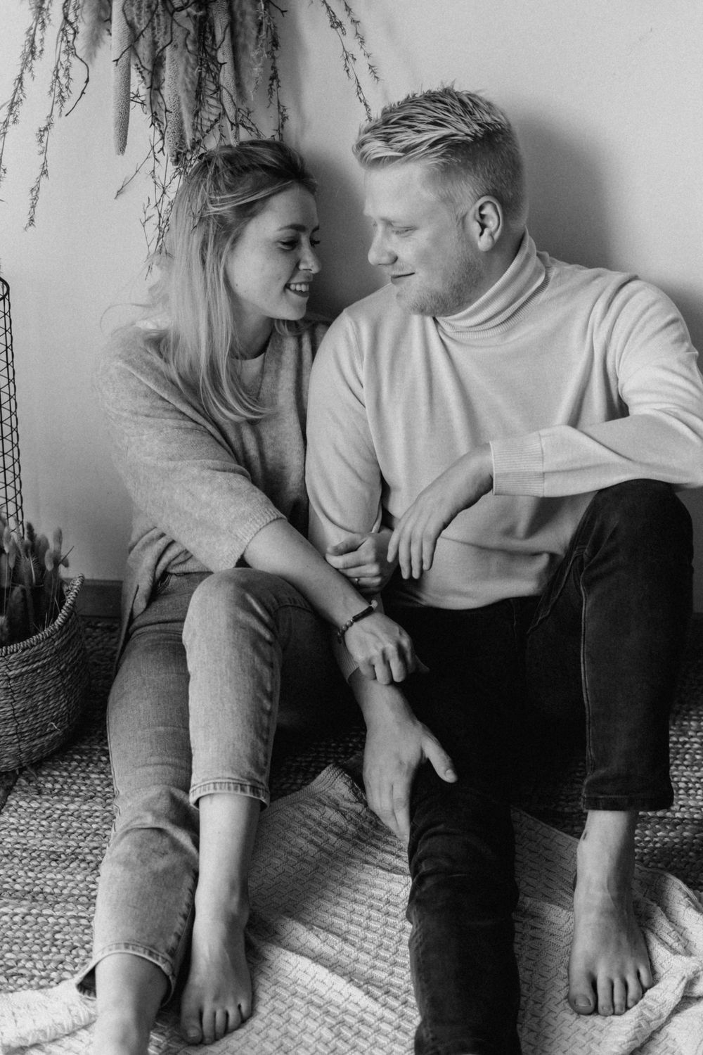 A romantic black and white image of a couple sitting together on a carpeted floor, sharing an intimate moment.