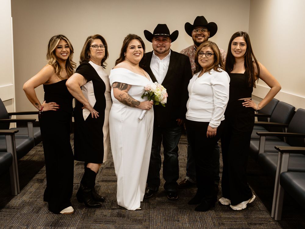 A wedding party poses together in a room with black and white formal attire creating an elegant contrast.