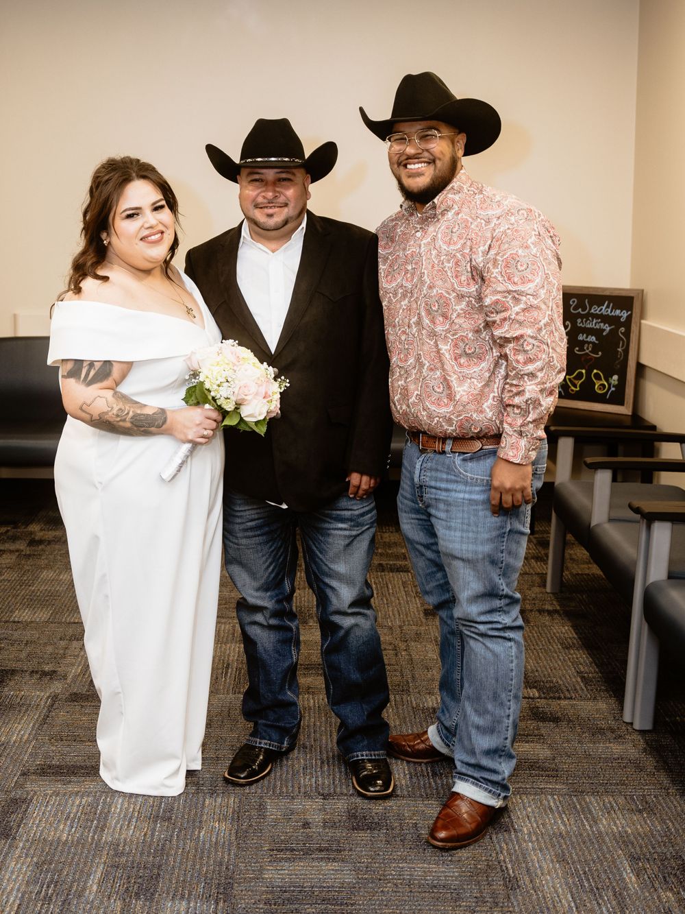Small wedding gathering features western attire with cowboy hats and a bride in white holding a bouquet.