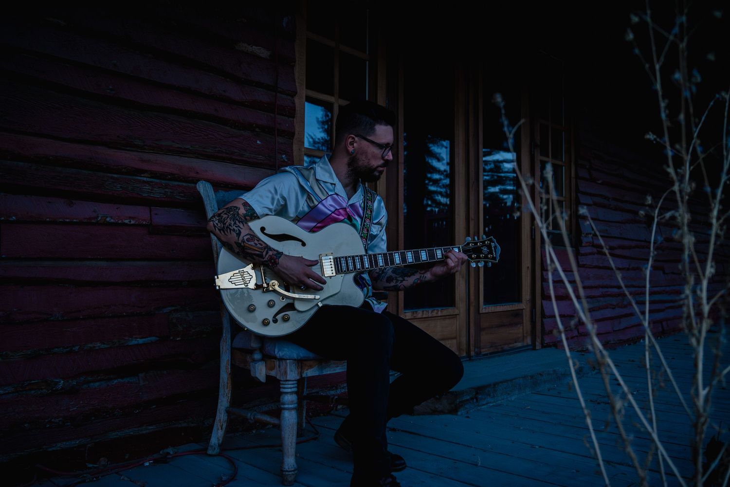 Outdoor male musician branding shoot during blue hour, holding a guitar with raw, authentic vibes.