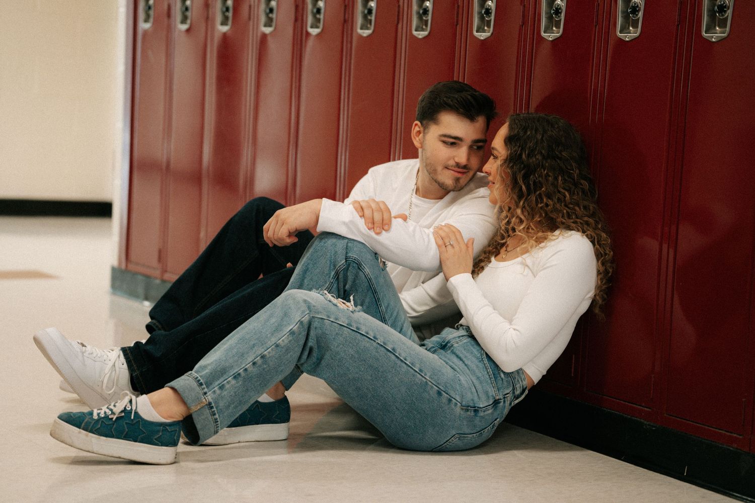 Highschool sweethearts nuzzled up in front of the lockers they fell in love at