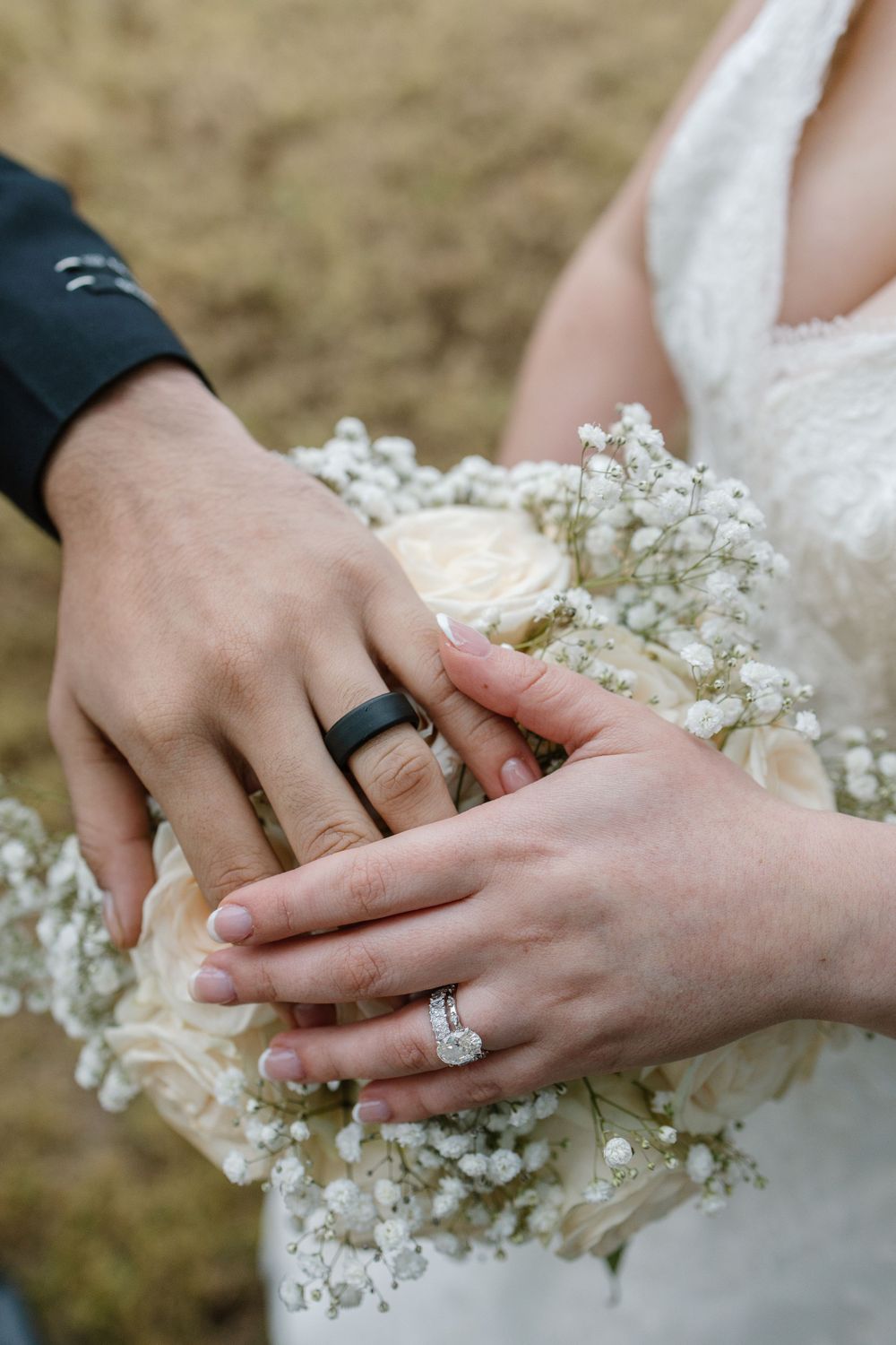 Wedding rings displayed with baby's breath flowers in a romantic close-up shot of hands.