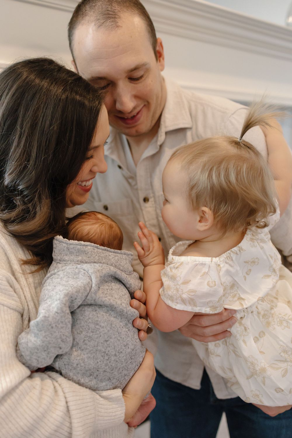 Family shares intimate moment together with newborn and toddler at home.