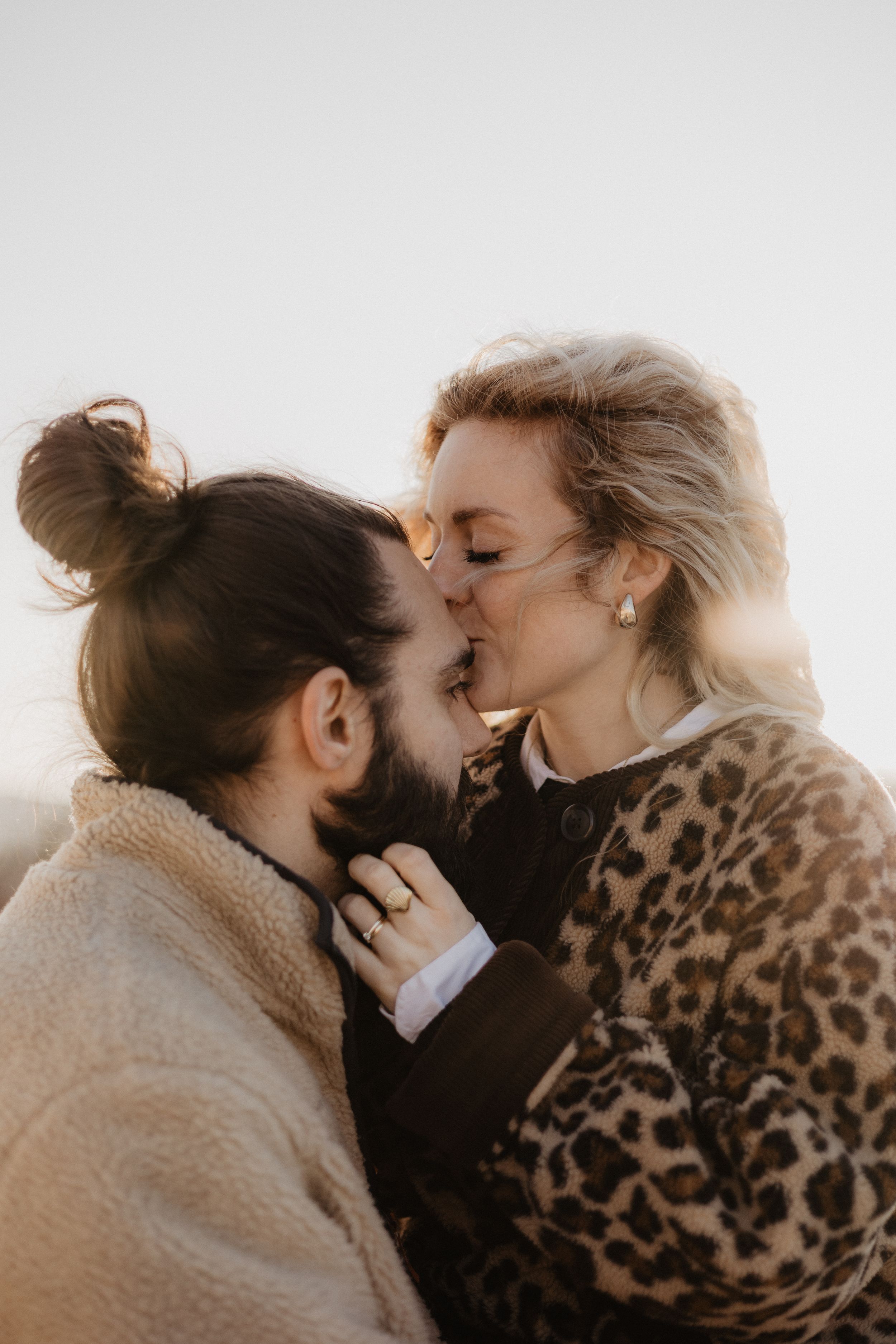 An intimate moment between two people wearing leopard print and neutral tones in soft lighting.