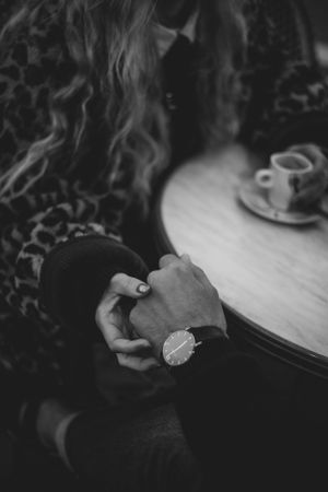 Close-up of hands with a wristwatch against a leopard print fabric and coffee cup on table.
