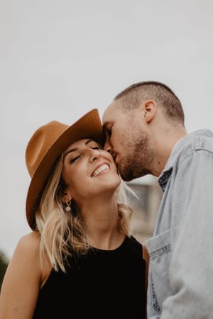 Photo d'un couple lors d'une séance photo. L'homme embrasse la femme sur la joue.