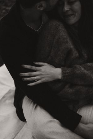 An intimate black and white photo showing affectionate embrace in soft lighting.