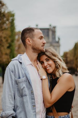 Photo d'un couple qui se câlinent. La femme regarde l'objectif en souriant.