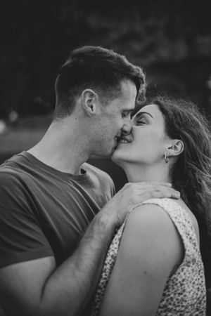 An intimate black and white portrait of a couple sharing a tender moment outdoors.