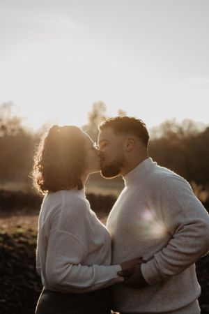 Photo d'un couple qui s'embrasse lors d'une séance photo dans un parc.