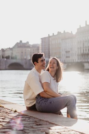 Photo d'un couple sur la Saône. Ils sont assis et se serrent dans les bras en se regardant tendrement.
