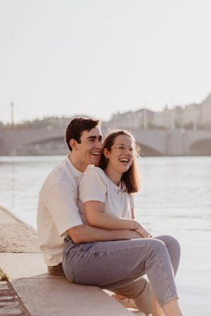 Photo d'un couple sur les bords de Saône. Ils sont assis et s'enlacent.